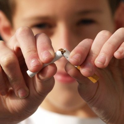 Close-up of man's fingers tearing apart a cigarette.